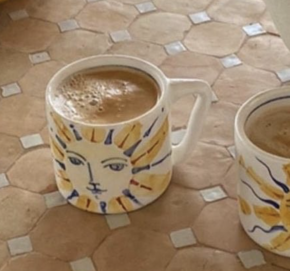 Warm sun-face coffee mug on terracotta tile